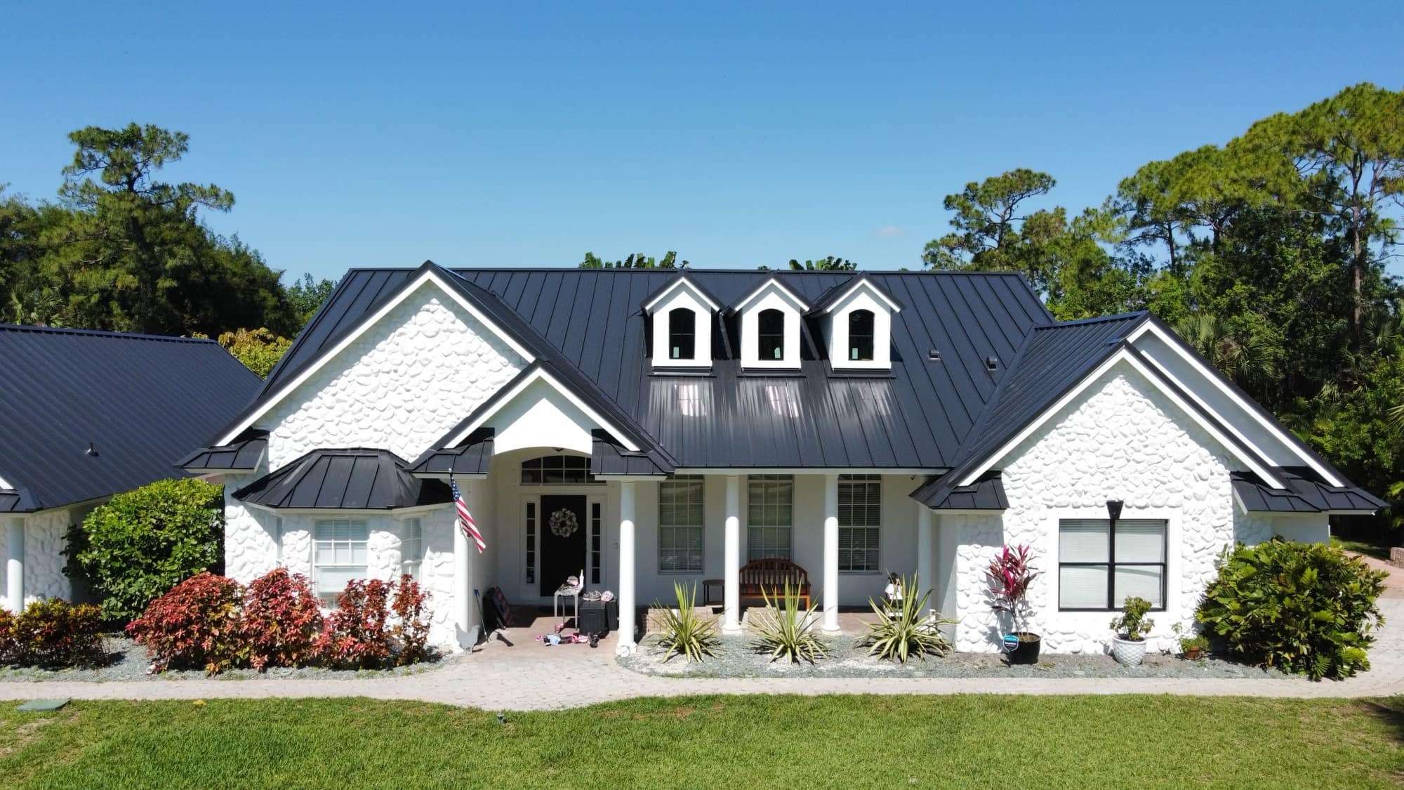 Elegant white house with black roof and lush greenery