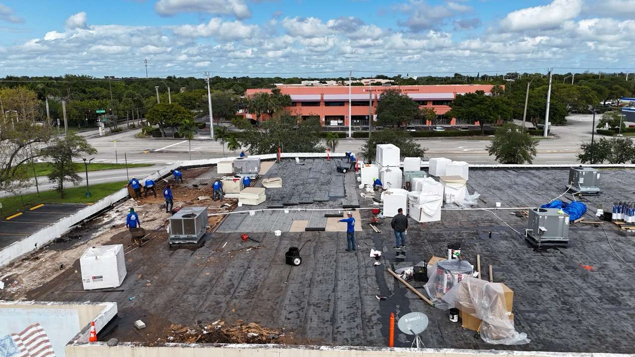 Workers repairing a large commercial building roof